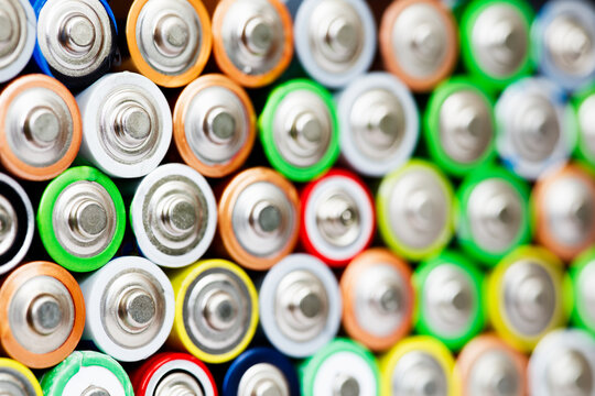 Closeup of pile of used alkaline batteries. Close up colorful rows of selection of AA batteries energy abstract background of colorful batteries. Alkaline battery aa size. Several batteries in rows.