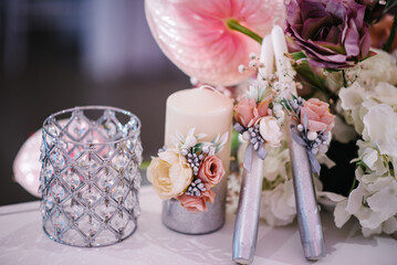 The candles decorated of white pink flowers on wedding table. Close up. Wedding decor for party.