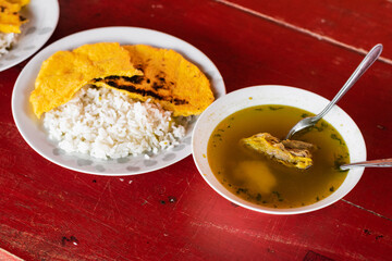 view from above of a delicious colombian breakfast made with beef broth, rice, yellow arepa and natural spices such as coriander and cimarron. typical dish of the colombian peasants.