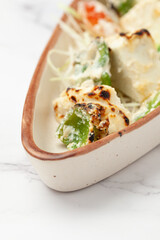 Close-Up of tandoori Malai Paneer tikka with bell pepper made with cottage cheese and cream and garnished with cabbage and ginger