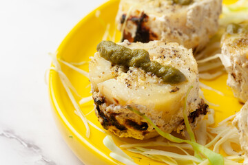 Close-Up of tandoori paneer stuffed potato with potato, cheese  with cottage cheese and cream and garnished with cabbage and ginger