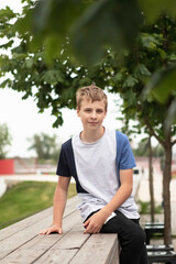 boy teenager sits on a wooden balustrade by the river in the city