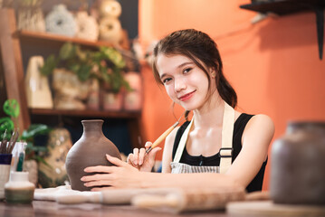 Small group of young caucasian woman enjoy painting on ceramic vase, workshop in hand craft studio, Art and hobby handmade concept.