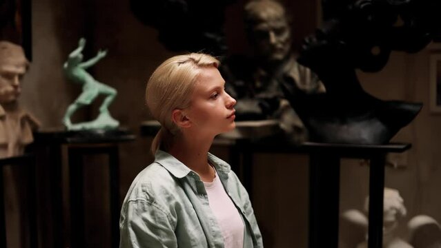 Portrait of attractive blonde woman sitting as a model in sculpture art studio while young sculptor create her beautiful portrait. Inspiration. Art.