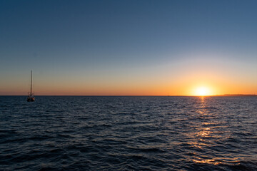 sunset over the sea with sailboat