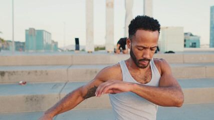 Young bearded male athlete jumps and makes movements with his hands during workout on the waterfront