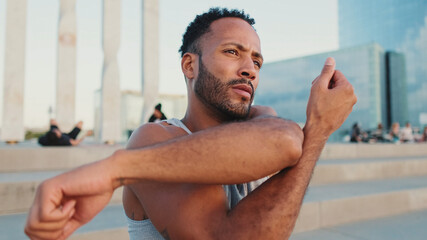 Young bearded male athlete jumps and makes movements with his hands during workout on the waterfront