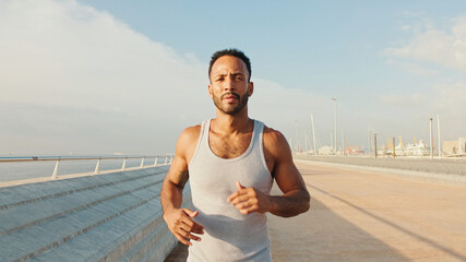 Young bearded male fit athlete runs along the promenade