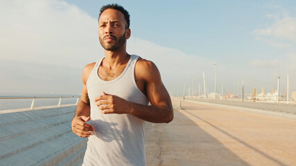 Young bearded male fit athlete runs along the promenade