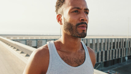 Close up, young bearded male fit athlete walks after training on the embankment