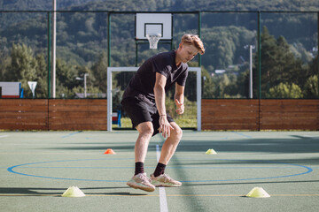 active hockey player is preparing for the outdoor season. The blond athlete sprints between the cones and slows his movement. Braking force applied to the ankle. Outdoor field