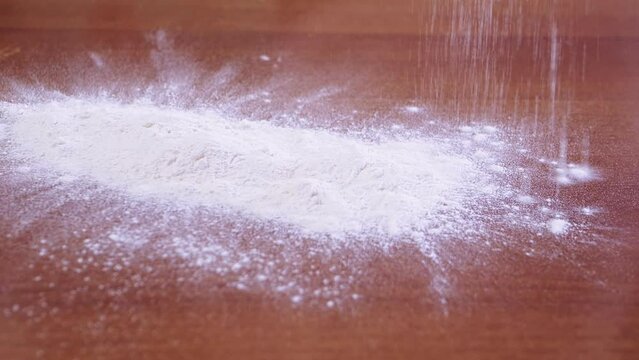 The hands of a Jewish woman sprinkle flour on a baking table