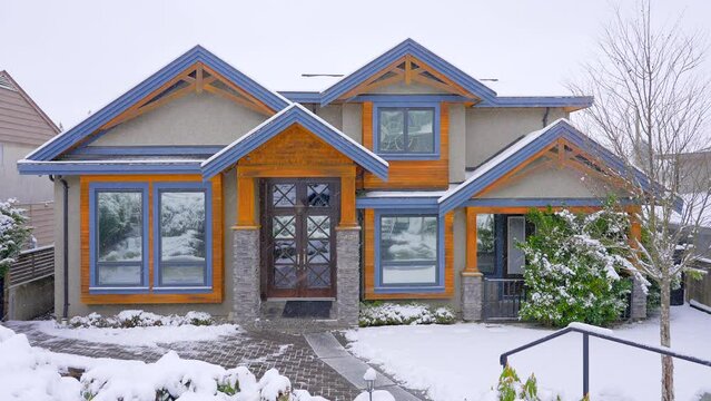 Establishing shot of two story stucco luxury house with big tree and nice landscape at winter snowfall in Vancouver, Canada, North America. Day time on December 2021. ProRes 422 HQ.