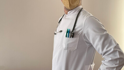 A doctor in a white coat, yellow mask, gray stethoscope, copy space