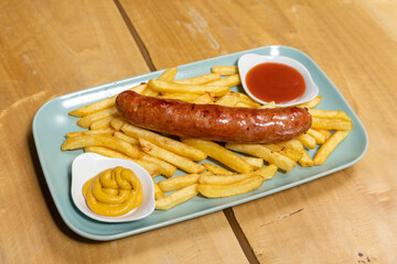 Grilled sausages served with french fries with dips on a plate