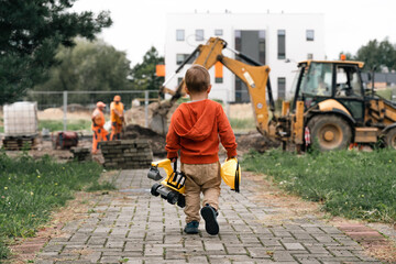 Child with excavator near construction site, dreams to be an engineer. Little builder. Education, and imagination, purposefulness concept - 533214030