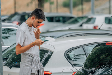 young man with mobile phone looking at cars