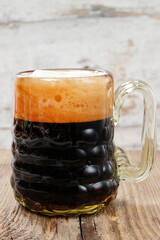 Glass of dark beer on wooden table.
