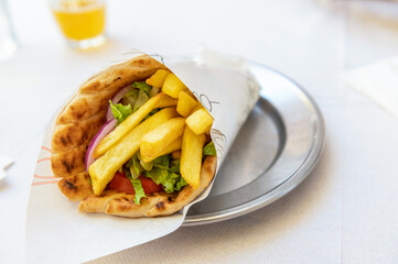 Greek vegetarian gyros with french fries, halloumi cheese and fresh vegetables wrapped in pita and served in greek cafe