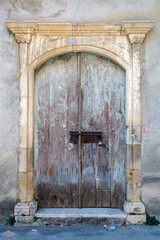 Fototapeta na wymiar Obsolete old wooden front door in stone doorway 