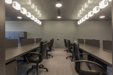 The working area of the office space with dark gray furniture and original lighting.