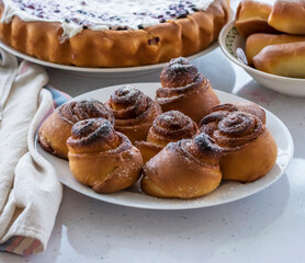 freshly baked buns and a pie with raspberry and blueberry cottage cheese on a white table.