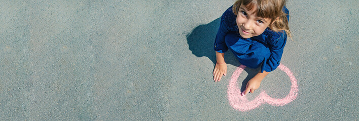 child draws with chalk on the pavement. Selective focus.