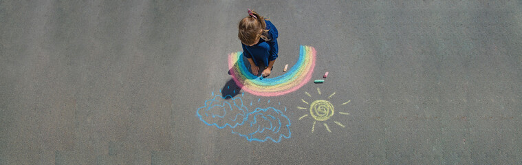 child draws with chalk on the pavement. Selective focus.