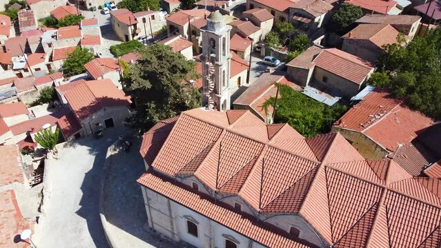 Aerial drone footage of traditional countryside village Lofou, Limassol, Cyprus. Close up of christian church Panayia Chrysolofitissa, ceramic tiled roof houses and cobbled narrow streets from above.