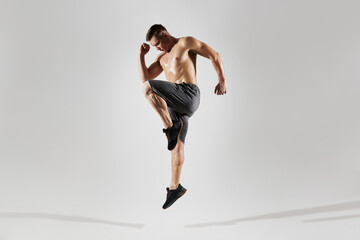 Handsome muscular man with perfect body jumping against white background