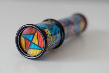 Close-up of a kid's kaleidoscope toy used to create abstract images while looking through the viewfinder. Selective focus. - obrazy, fototapety, plakaty