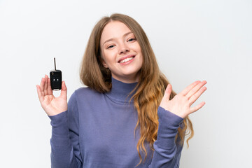 Young caucasian woman holding car keys isolated on white background saluting with hand with happy expression