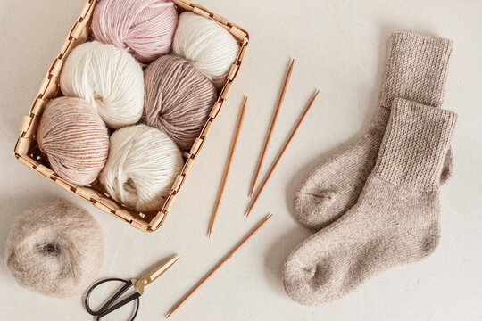 Craft hobby background with yarn in natural colors and handmade socks. Recomforting hobby to reduce stress for cold fall and winter weather. Mock up, top view