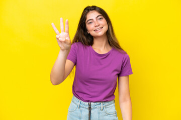 Young caucasian woman isolated on yellow background happy and counting three with fingers