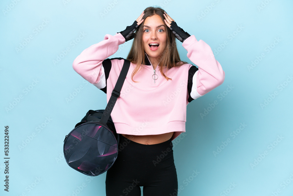 Wall mural Young sport woman with sport bag isolated on blue background with surprise expression