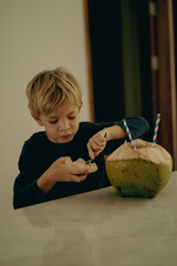 Fototapeta premium Little boy child drinks coconut water from a fresh coconut.
