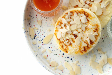 White plate with fried curd pancakes or syrniki, horizontal shot, sprinkled with almond flakes. Top view, macro