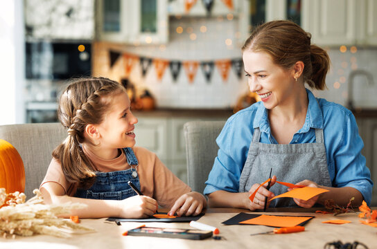 Happy smiling family mother and daughter making Halloween home decorations together