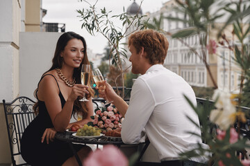 Beautiful young couple toasting with champagne while having a romantic dinner on the balcony