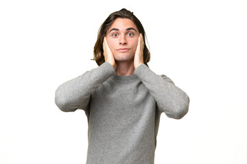 Young caucasian man isolated on green chroma background frustrated and covering ears