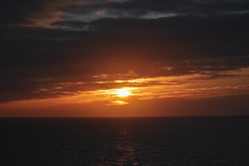 bright orange yellow sunrise sunset over ocean reflection in sea 