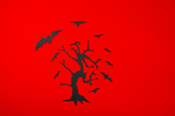 Halloween black carved tree with flying bats on the red background..