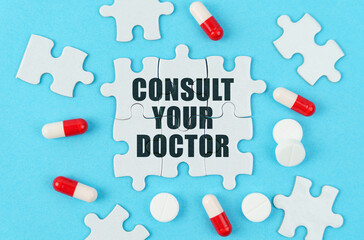 On a blue background, pills, capsules and puzzles with the inscription - Consult your doctor