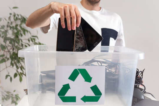 Man throwing away broken mobile phones in recycle container. Hazardous E-Waste Recycling. Waste Electrical and Electronic Equipment.