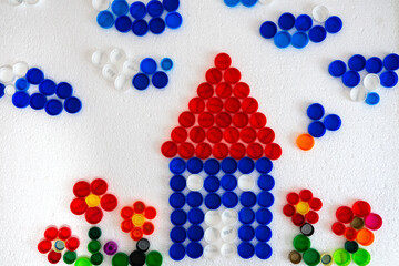 House mosaic decoration made of colorful plastic bottle caps . Handmade crafts. Recycling art.