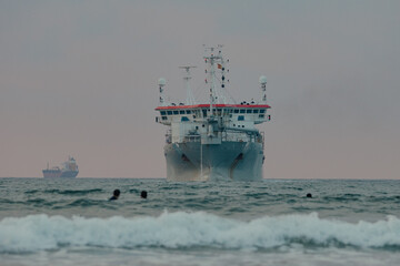 large industrial ship in the middle of the sea during a surf and travel week experience in Somo,...