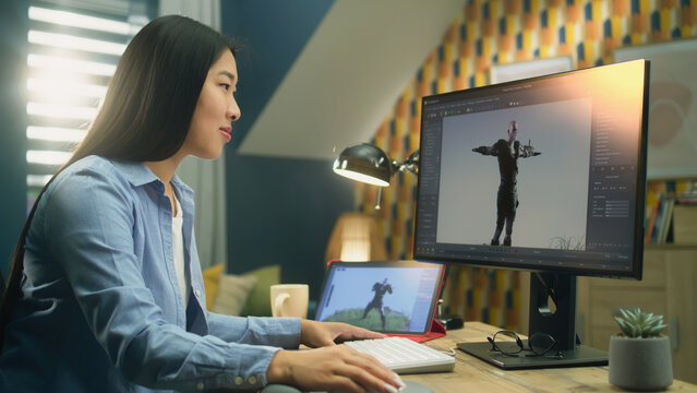 Asian female 3D designer making animation for video game character using modern computer and tablet and software for creating 3D modeling projects
