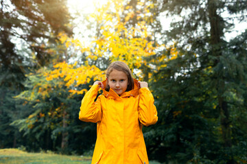 little cute girl in yellow raincoat walking in autumn forest.