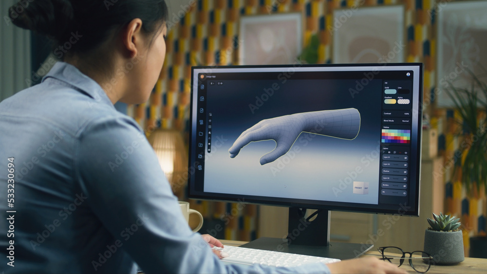 Poster woman sitting at the table at home office and making 3d prototype of human hand in professional prog