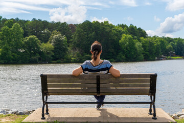 person sitting on a bench watching a lake.